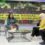 A woman sits with two hosts in a studio during a live TV news programme in Malaysia.