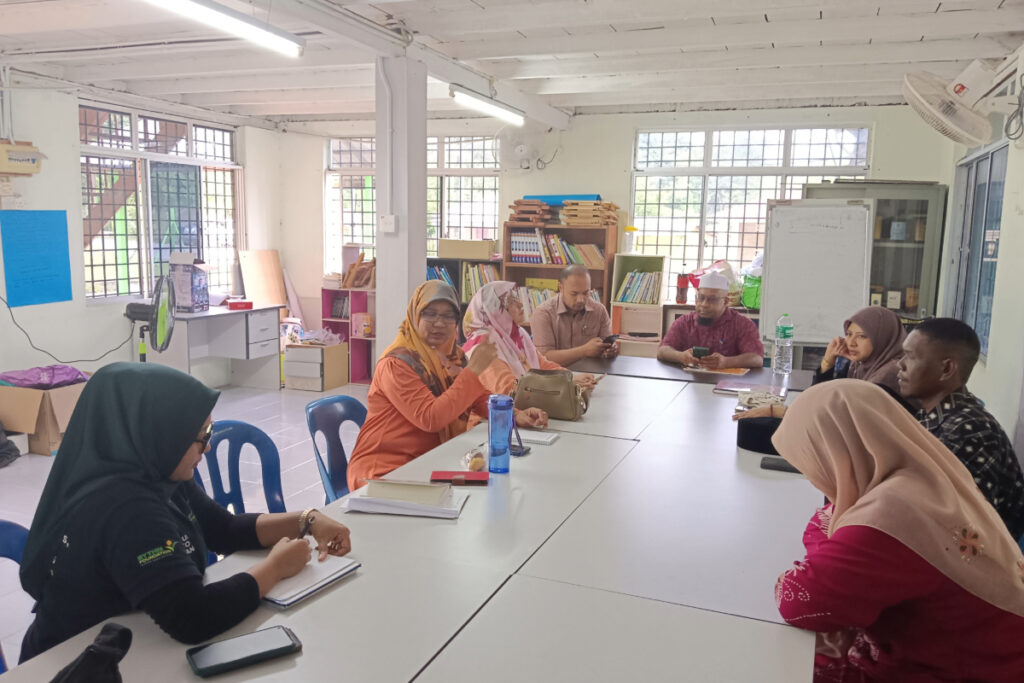 A group of people engaged in discussion while seated around a table in Kampung Lubuk Legong in Baling, Kedah, Malaysia.