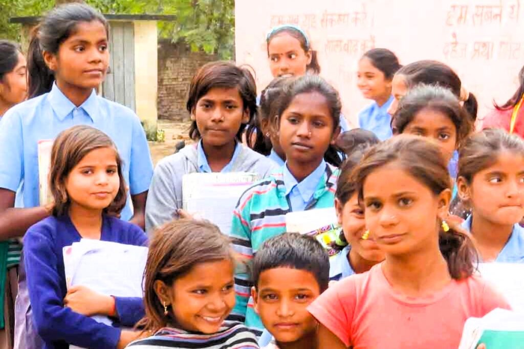 A group of rural children in West Bengal, India, holding books and posing outdoors.