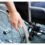 A person sitting in a wheelchair, with one hand visible gripping the wheel.