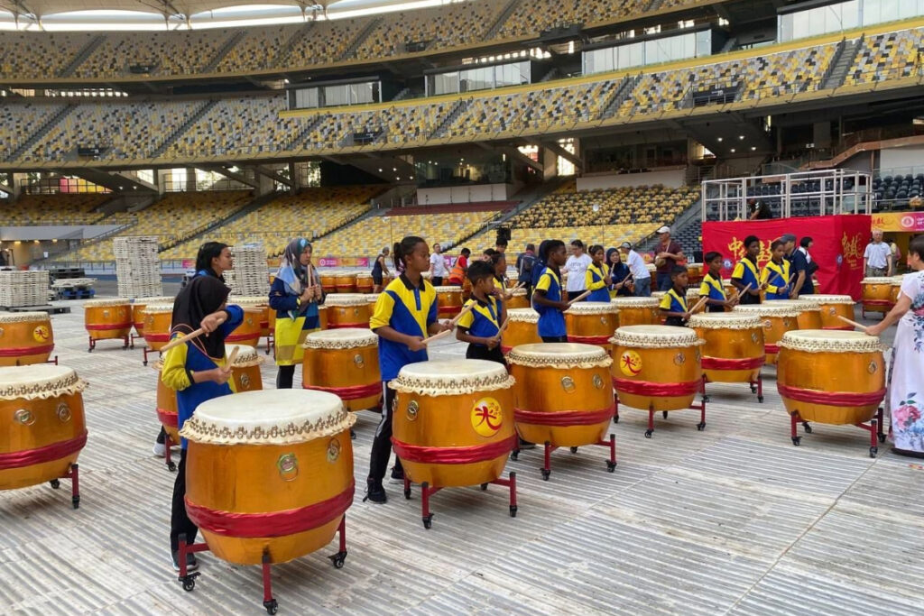 Bateq Orang Asli children stand behind Oriental drums in the front row at Bukit Jalil Stadium in Kuala Lumpur, Malaysia.