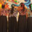 A group of girls with their backs to the camera, arms over each other's shoulders, standing in front of a vibrant, colourful mural.