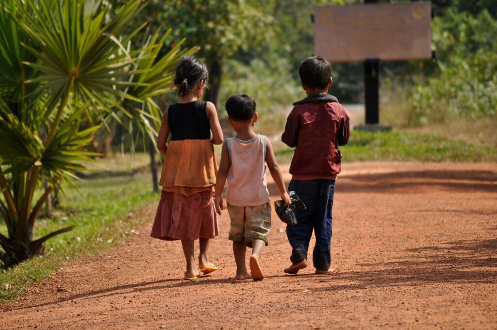 Children in Southeast Asia walking away on a dirt path. Photo by Aleks Habarovs.